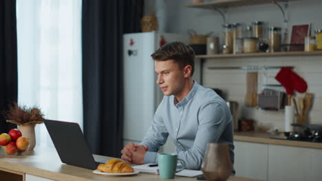 man conducting video conference sitting at kitchen. businessman using webcam.