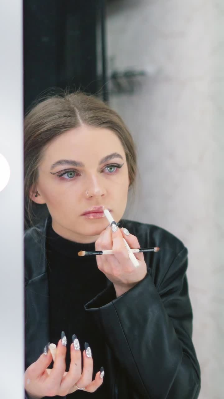 Woman applying makeup and holding beauty tools