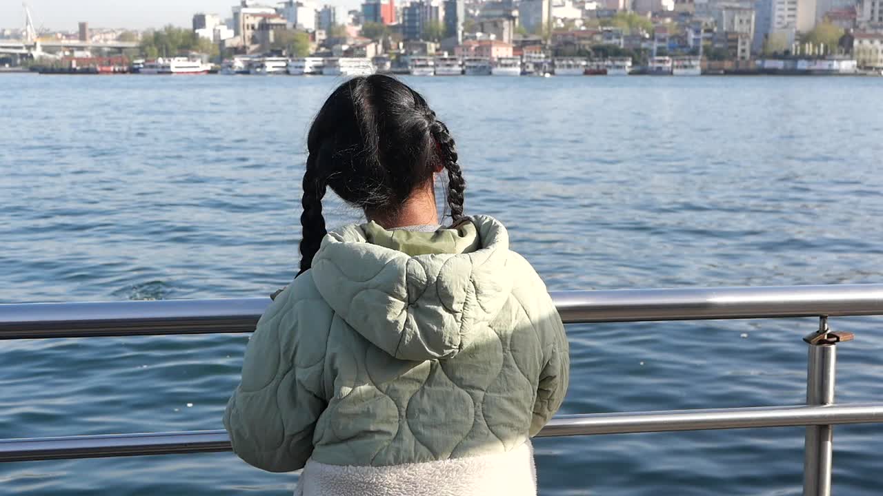 Child looking at a city across the water