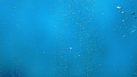 a stream of rising air bubbles under water on blue background a stream of rising air bubbles under water on blue background close up of oxygen bubbles in blue ocean sea water or shot through the glass in an aquarium aeration filtration liquid carbonization slow motion