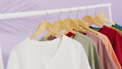 Video-of-close-up-of-multiple-t-shirts-hanging-on-purple-background