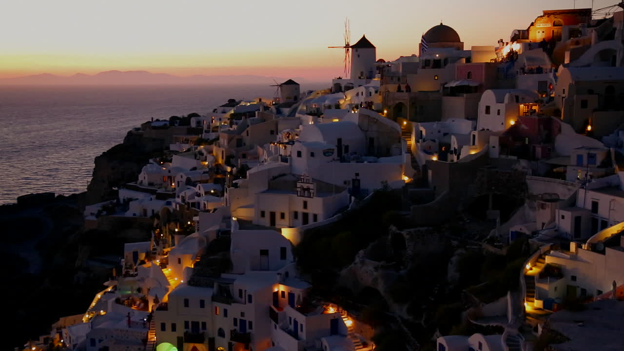 molinos de viento bordean las laderas de la romántica isla griega de santorini al atardecer