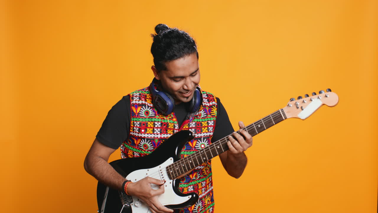Uomo felice che tiene una chitarra elettrica, suona musica rock, su sfondo in studio