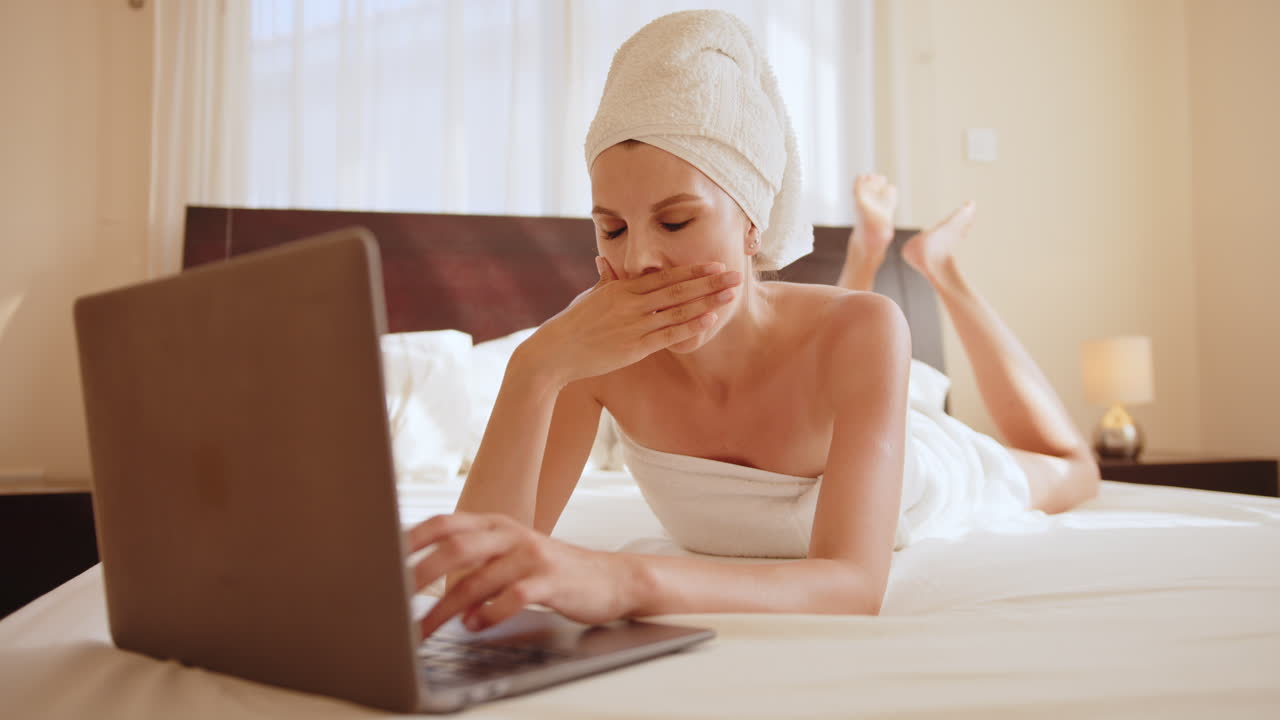 Donna che si rilassa a letto con il portatile