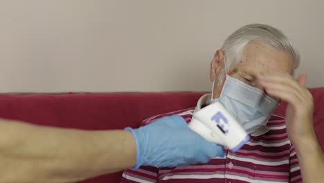 los médicos miden la temperatura con un termómetro electrónico para el abuelo enfermo.