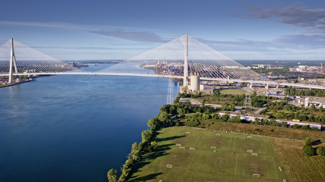 Drone footage traveling across the Gordie Howe Bridge toward the factories by the river