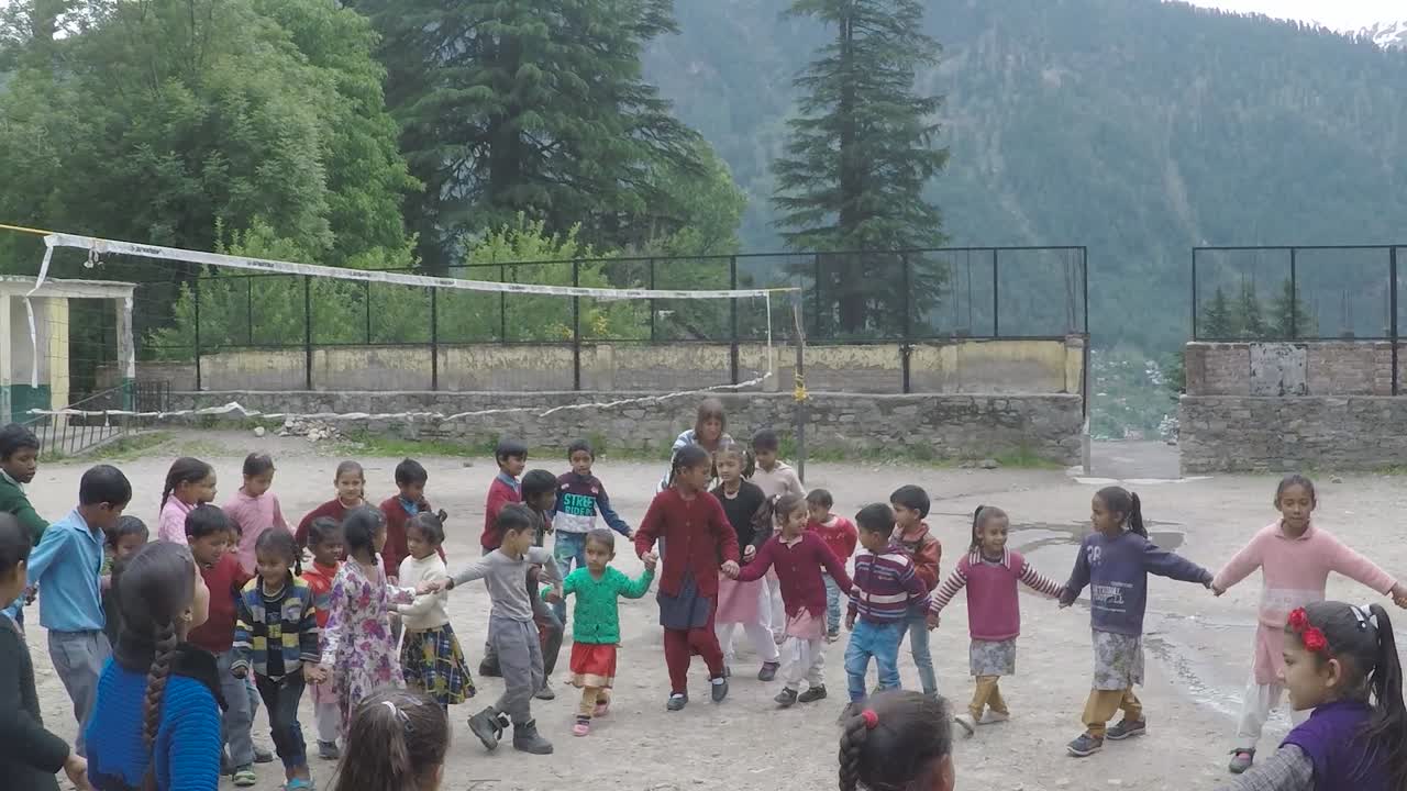 Manali, India, circa 2019 - Western woman gets young children into a circle in an activity, at a village school in the Himalayas