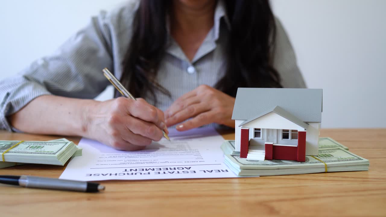 Woman Buying a House Signing the Real Estate Purchase Agreement. - closeup shot
