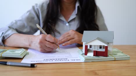 woman buying a house signing the real estate purchase agreement. - closeup shot