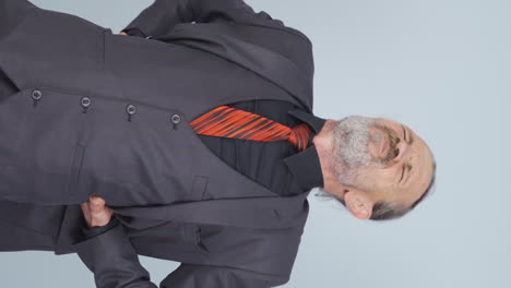 video vertical de un viejo hombre de negocios experimentando dolor de espalda.