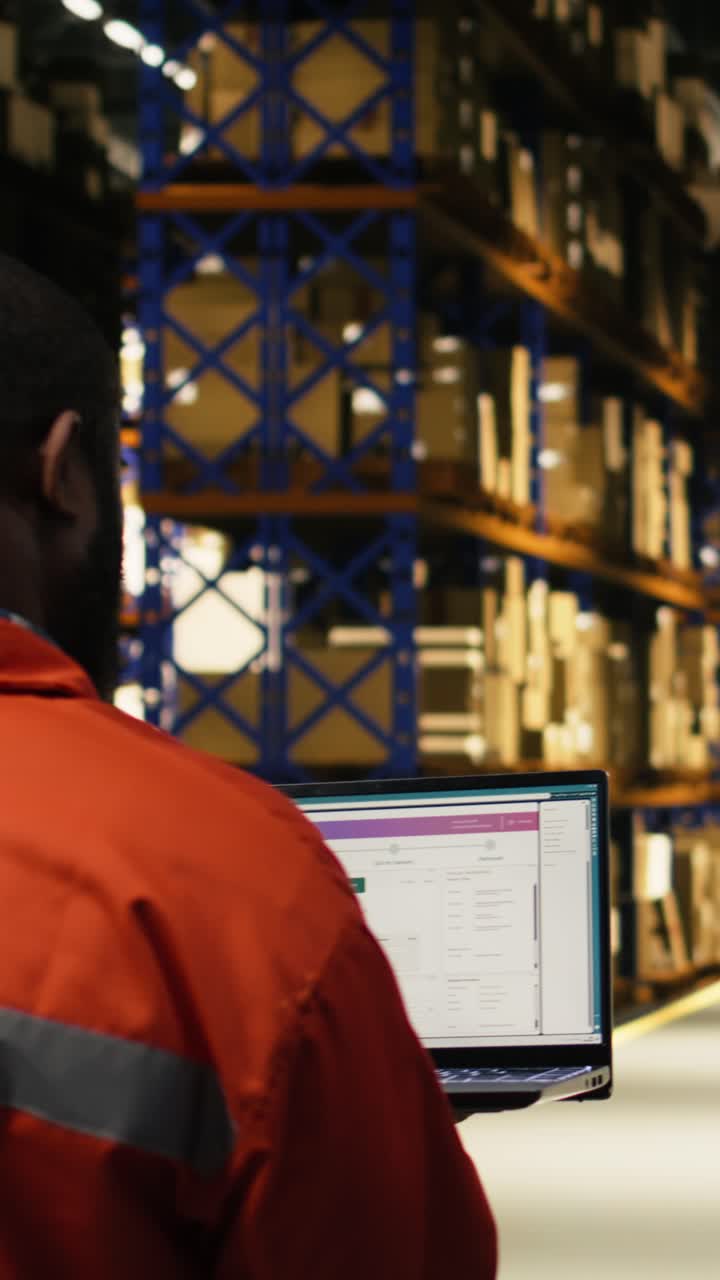 Video verticale: Impiegato afroamericano che gestisce la logistica dei pacchi al laptop.