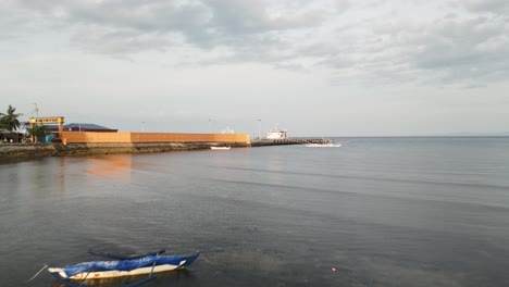 aerial dolly above of the serene taloot argao port at sunrise in cebu, philippines, with boats and double hull canoes anchored near the pier