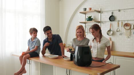 the caucasian family make breakfast with the air fryer together.  father, mother, daughter and sons cooking in the kitchen together at home. happy family relationship and technology concept