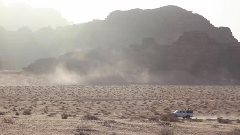 car driving through arid desert, dust mountains at the background, wadi rum, jordan, panoramic shot