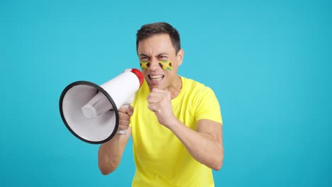 excited man with jamaican flag on face using a megaphone
