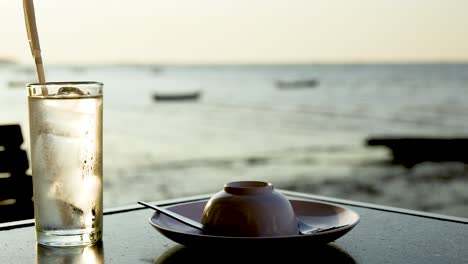 glass and dish by the beach at sunset