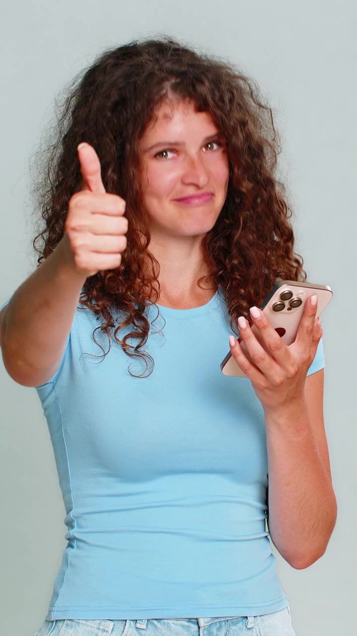 Donna che scorre il feed di notizie dello smartphone, sorride e fa un gesto di "mi piace" con il pollice in su, reazione positiva.