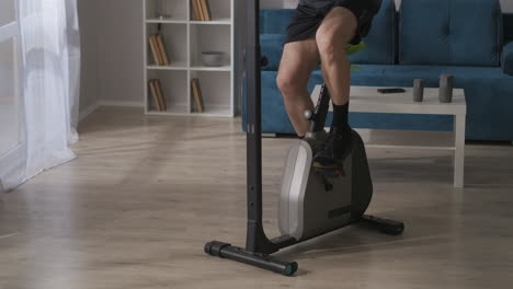 hombre deportivo está girando los pedales de la bicicleta de ejercicio en casa detalles ver entrenamiento y mantener su condición física deporte y actividad