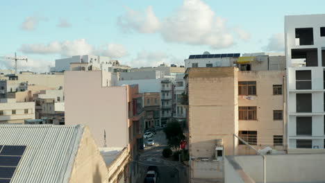 Drone-Aéreo-Hacia-Adelante-A-Través-De-La-Calle-De-Malta-Y-Sobre-Los-Tejados-Que-Revelan-El-Paisaje-Urbano-Con-Cielo-Azul-Y-Nubes