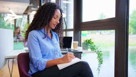 Businesswoman-Working-At-Desk-In-Office-Taking-Call-Talking-Into-Mic-Of-Mobile-Phone