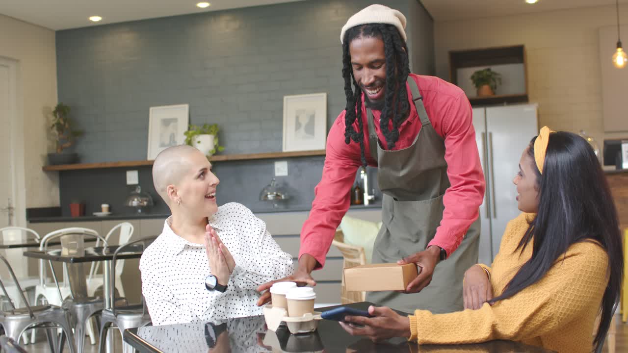 Barista nähert sich und löst die Begrüßung verschiedener Freundinnen aus, während diese im Café mit dem Handy bezahlen
