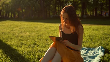 mujer joven relajada usando una tableta al aire libre