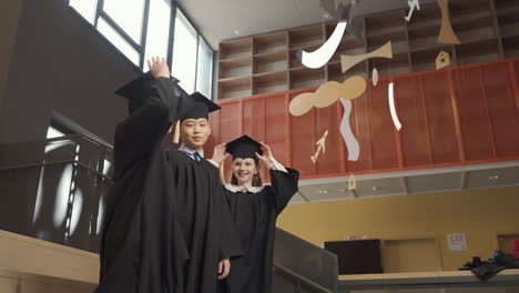 happy  students throwing their mortarboards up in the air 3