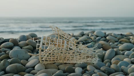 trampa de peces descartada en la playa de guijarros, basura en la playa