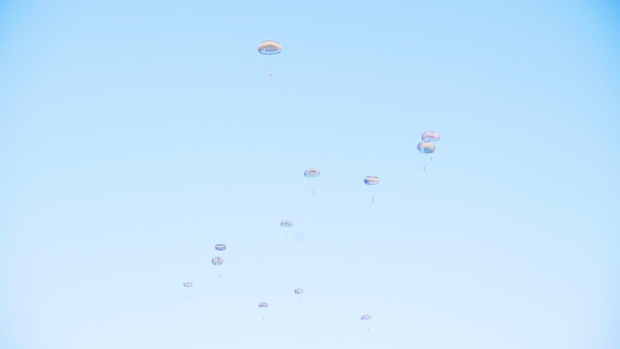 군용 스카이 다이빙 연습 중에 밝은 파란 하늘을 배경으로 조율된 패턴을 형성하는 중간 하강의 낙하산 선수 그룹