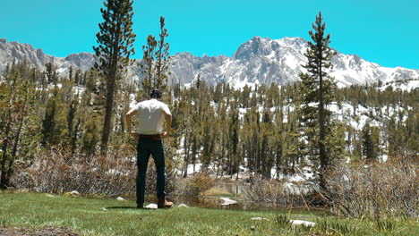 Photographer-examines-the-landscape-with-alpine-lake-and-snowy-mountain-peaks