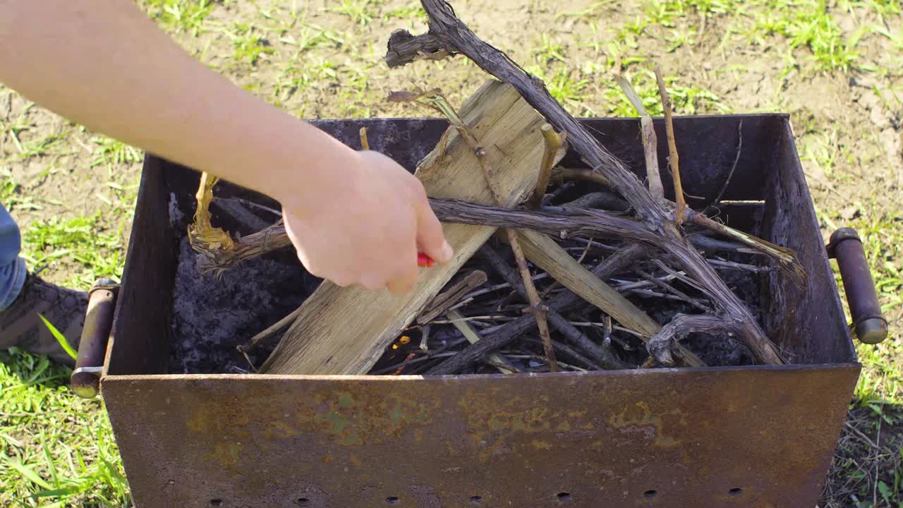 그 남자는 바베큐에서 불을 피운다.
