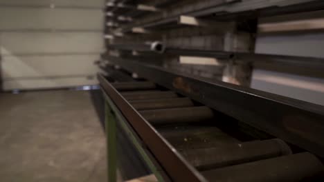 in the metal manufacturing warehouse there is metal bar sliding on the rollers