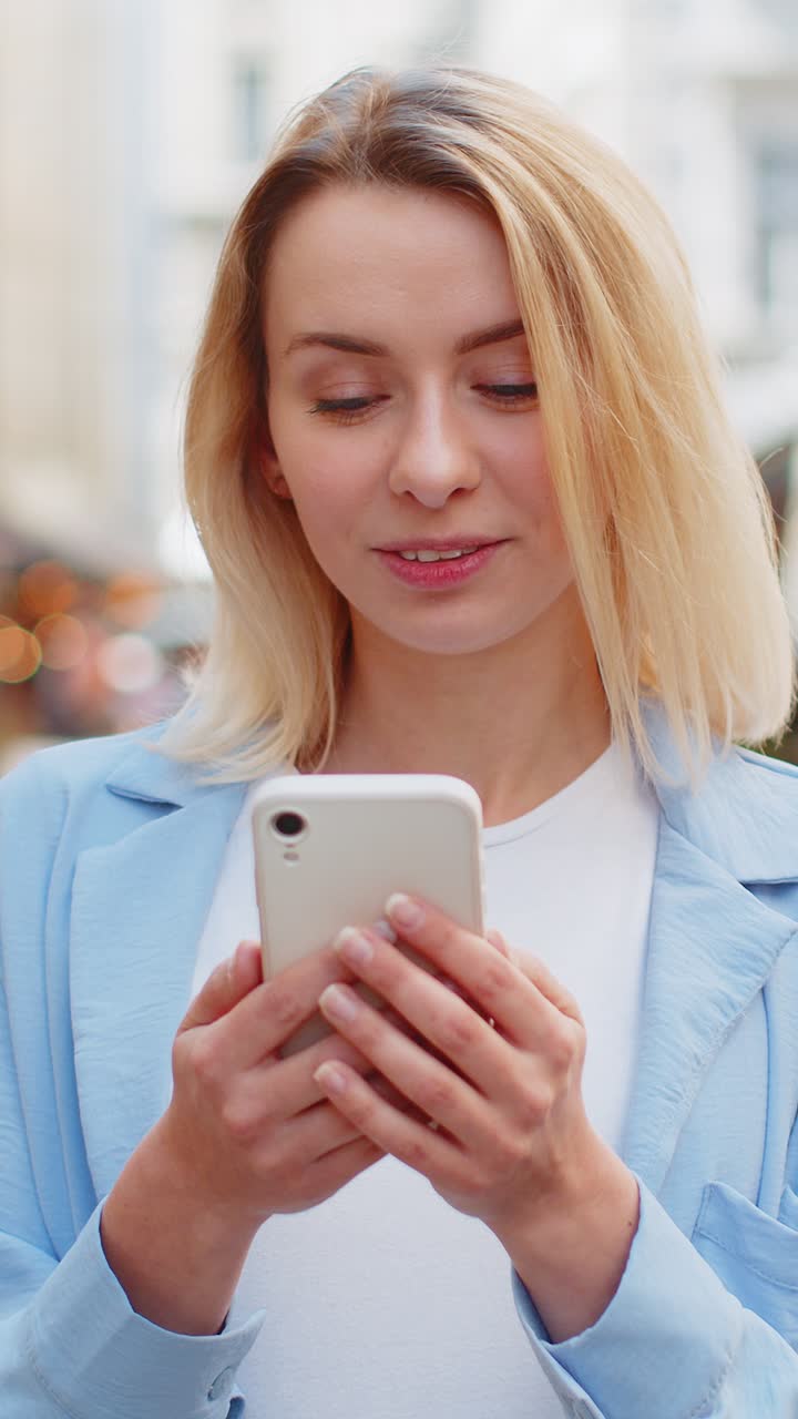 Donna che usa lo smartphone mobile, scrive messaggi di testo, naviga su Internet, finisce il lavoro e guarda la telecamera.