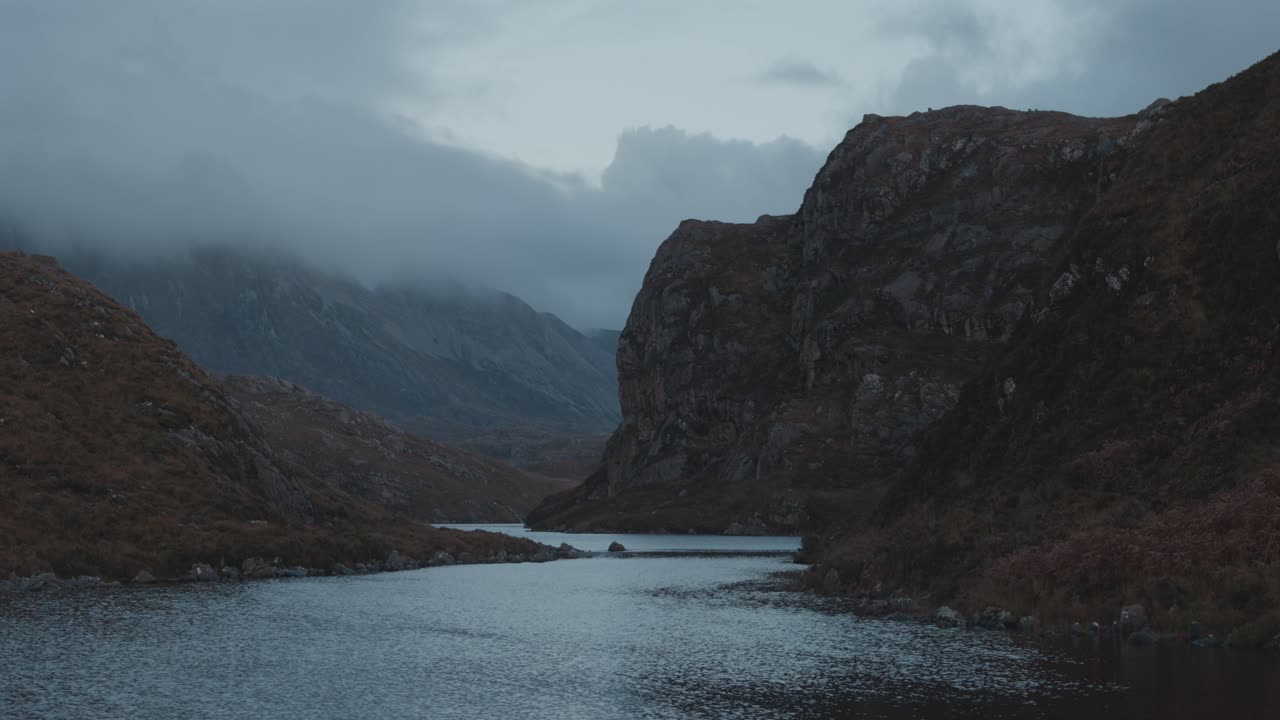 Immagine statica della gola di Loch na Thull, acqua e scogliere incorniciate da nuvole in movimento, una scena malinconica delle Highlands dai toni naturali