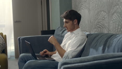 Smiling-man-using-laptop-in-hotel-room.-Handsome-guy-chatting-computer-indoors.