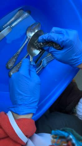 washing old silverware in a plastic bowl