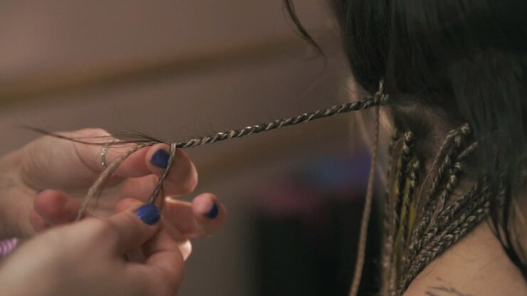 Close Up view of the hairdresser's hands doing dreads for a young woman in the hair salon. Slow Motion shot