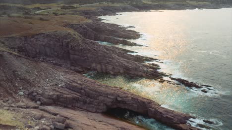 brillante luz solar reflejada en la superficie del océano con olas golpeando una costa escarpada en el este de canadá