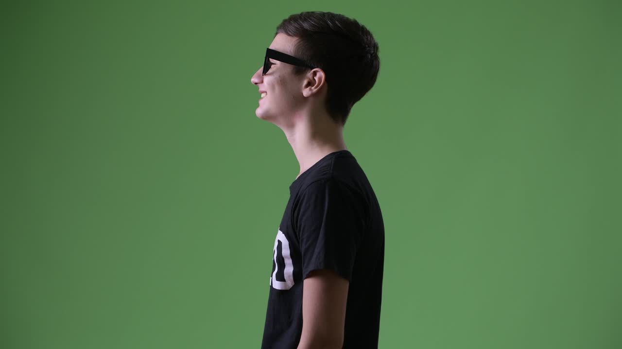 Young handsome Iranian teenage boy against green background