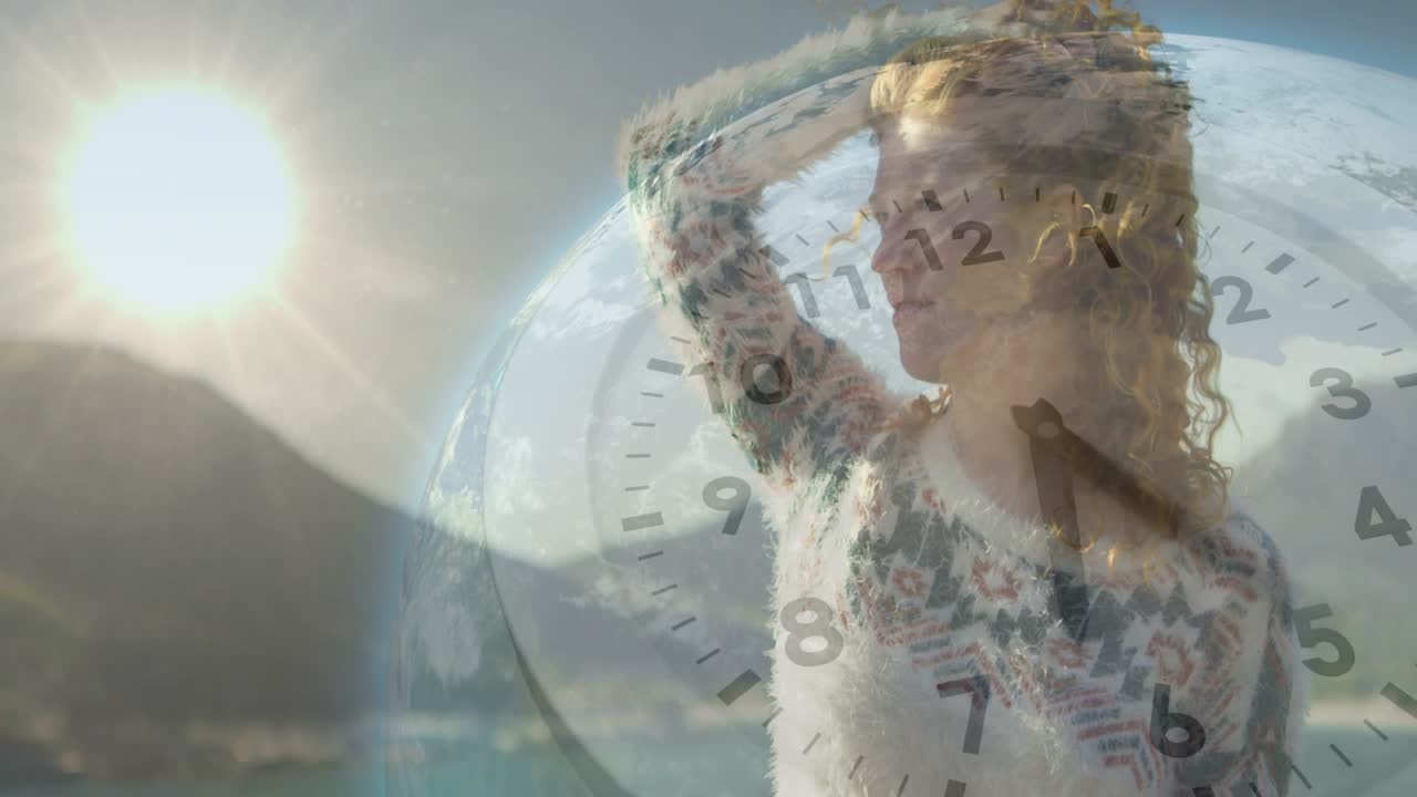 Donna che si ripara gli occhi e guarda verso la costa, con il sole che fa emergere sovrapposizioni digitali di orologio e globo per la tecnologia.