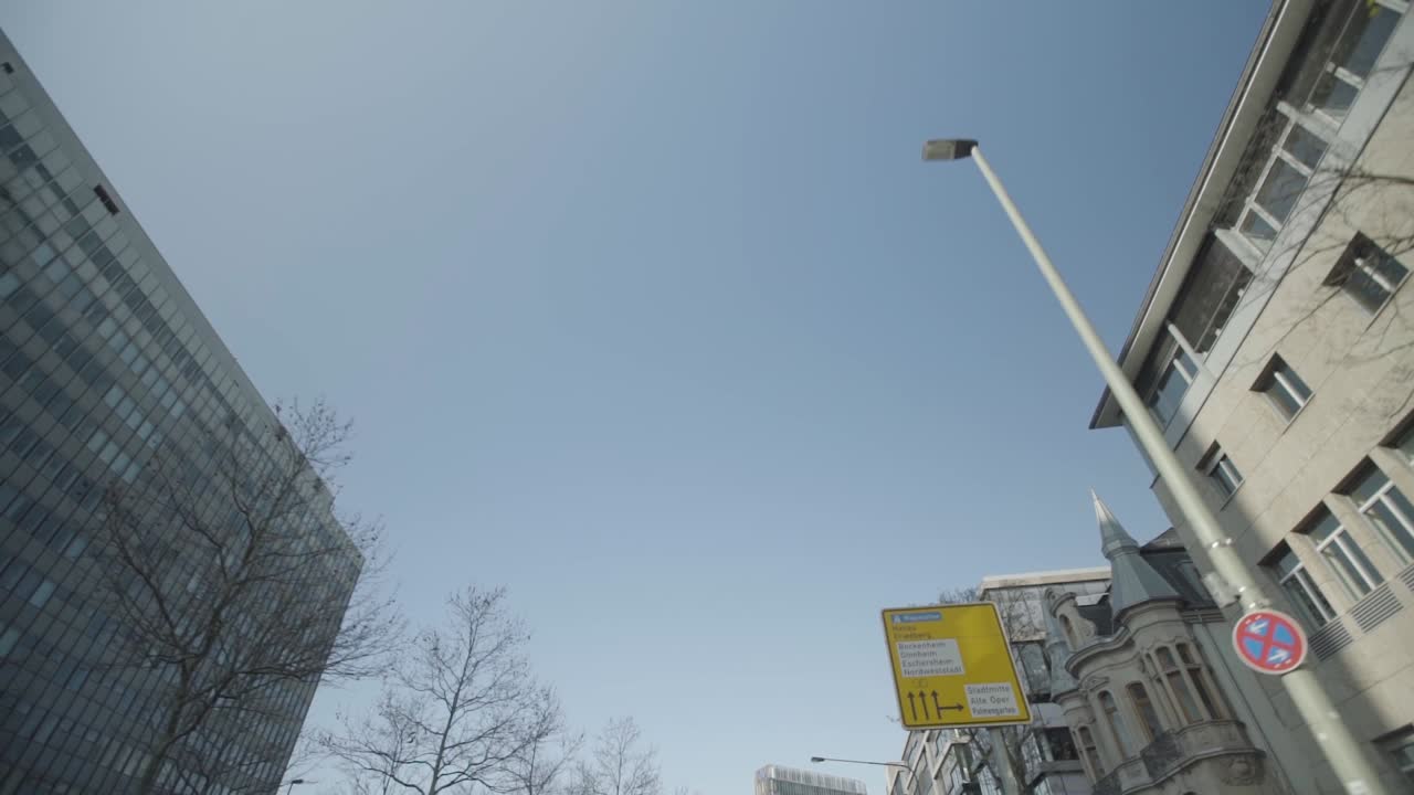 Looking up at buildings and street signs from a car's perspective on a clear day