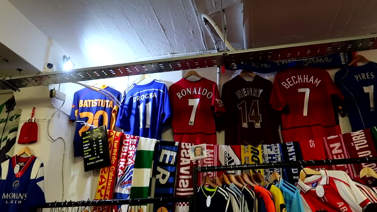 Ripresa panoramica di iconiche maglie da calcio in vendita in un mercato di strada vintage a Shoreditch.