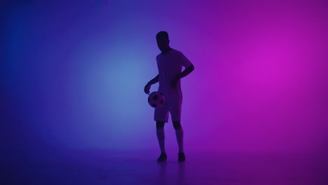 Slow-motion-portrait-of-a-black-professional-football-player-in-a-white-uniform-looking-into-the-camera-in-the-blue-red-neon-light-of-the-studio.-A-brutal-football-player-confident-and-victorious