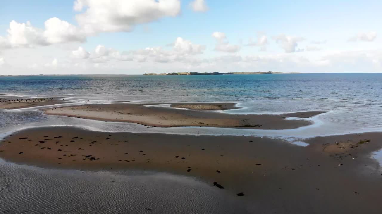 Aerial view flying across the sea in Sejerøbugten with flying seabirds and beautiful sandbanks