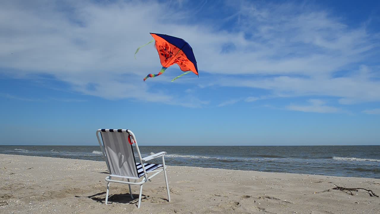 Liggestol på stranden, havet og en drage. Sommertid ved strandkanten