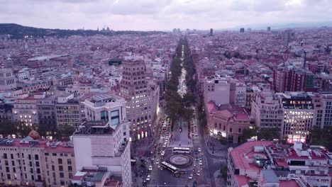 Barcelona-Al-Atardecer-Con-Las-Luces-De-La-Ciudad-Empezando-A-Brillar,-Tráfico-En-Las-Calles,-Vista-Aérea