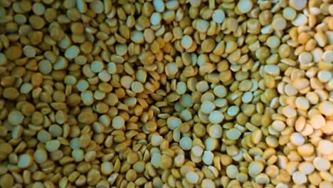 close-up of bengal gram rotating slowly in flour mill. 4k macro view of chana dal processing for food industry, agriculture and production visuals.