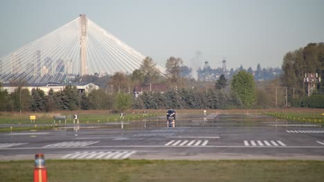 Airport-Inspection-Vehicle-Drives-on-Runway,-Port-Mann-Bridge-Backdrop