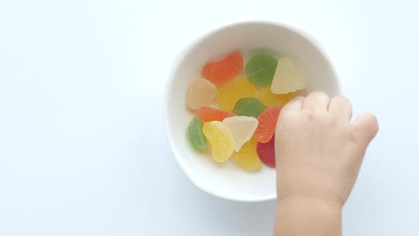 child reaching for gummy candies in a bowl