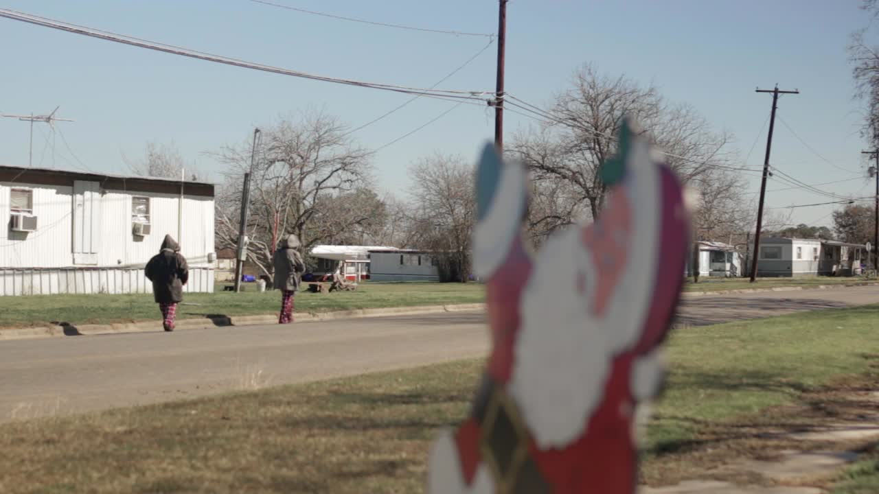 niños caminando por la calle detrás de la decoración navideña de santa